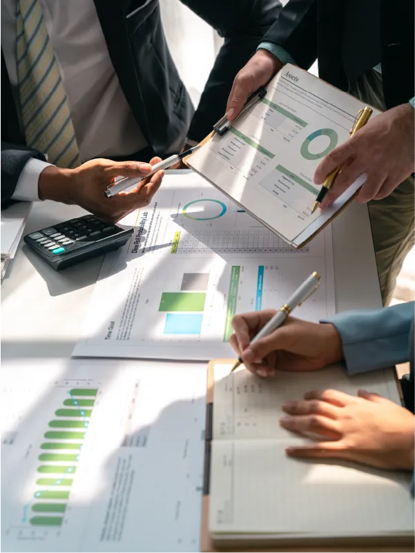 photo of desk with charts and people working